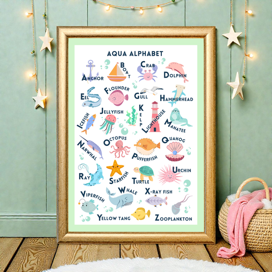 Framed children's poster with ocean-themed alphabet on a wooden floor with decorative lights and basket.