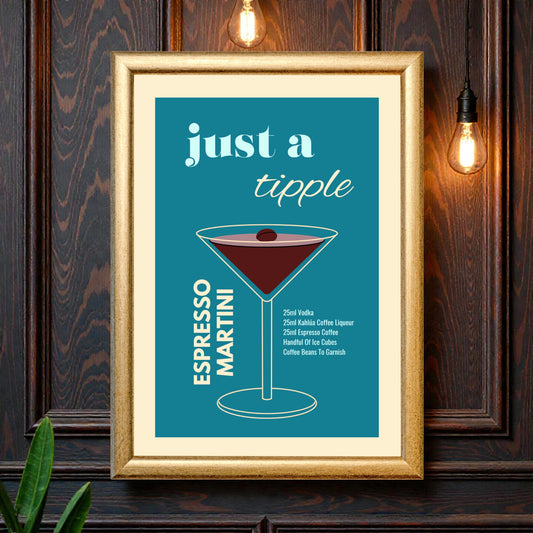 Framed espresso martini cocktail recipe wall art featuring a minimalist martini glass illustration on a teal background with the text “Just a tipple Espresso Martini,” styled against a dark wood wall with warm hanging lights.
