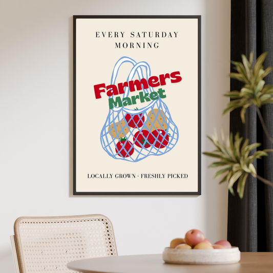 Framed poster with 'Farmers Market' design on a wall above a table with fruit.