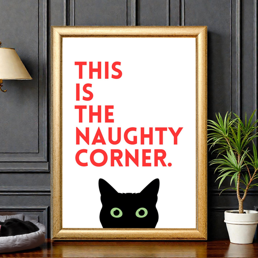 Framed funny cat wall art featuring bold red typography reading “This is the naughty corner” with a black cat illustration peeking from the bottom, styled on a shelf against a dark panelled wall.