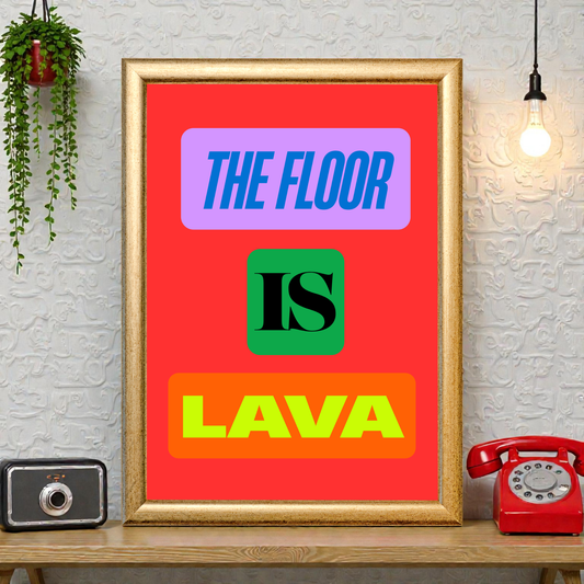 Framed “The Floor Is Lava” typography art print with bold colourful text on a red background, styled on a shelf with plants, a vintage camera, and a red telephone.