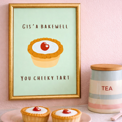 Framed artwork of a Bakewell tart with text on a pink wall, next to two cupcakes and a 'TEA' jar.