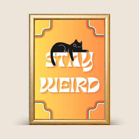 A framed art print featuring a black cat silhouette lying on the word 'STAY' above the word 'WEIRD' in large white letters, set against a yellow-to-orange gradient background with retro wavy corner accents. The print is enclosed in a gold frame and shown against a light beige background.