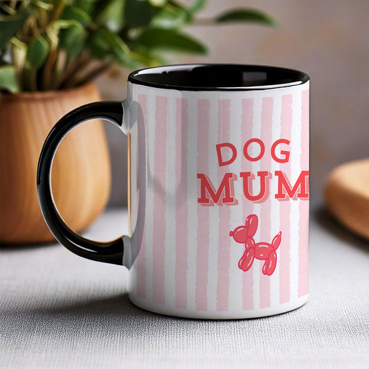 Mug with 'Dog Mum' text and dog illustration on a striped background, placed on a surface with a plant in the background.