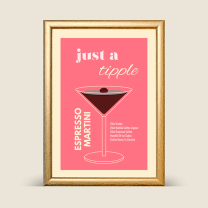 A gold-framed espresso martini illustration print on a pink background, featuring minimalist typography and a cocktail recipe, displayed against a neutral backdrop.