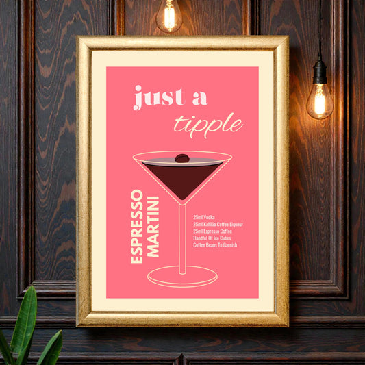 Framed espresso martini cocktail recipe wall art featuring a minimalist illustrated martini glass on a pink background with the text “Just a tipple Espresso Martini,” styled against a dark wood wall with warm hanging lights.