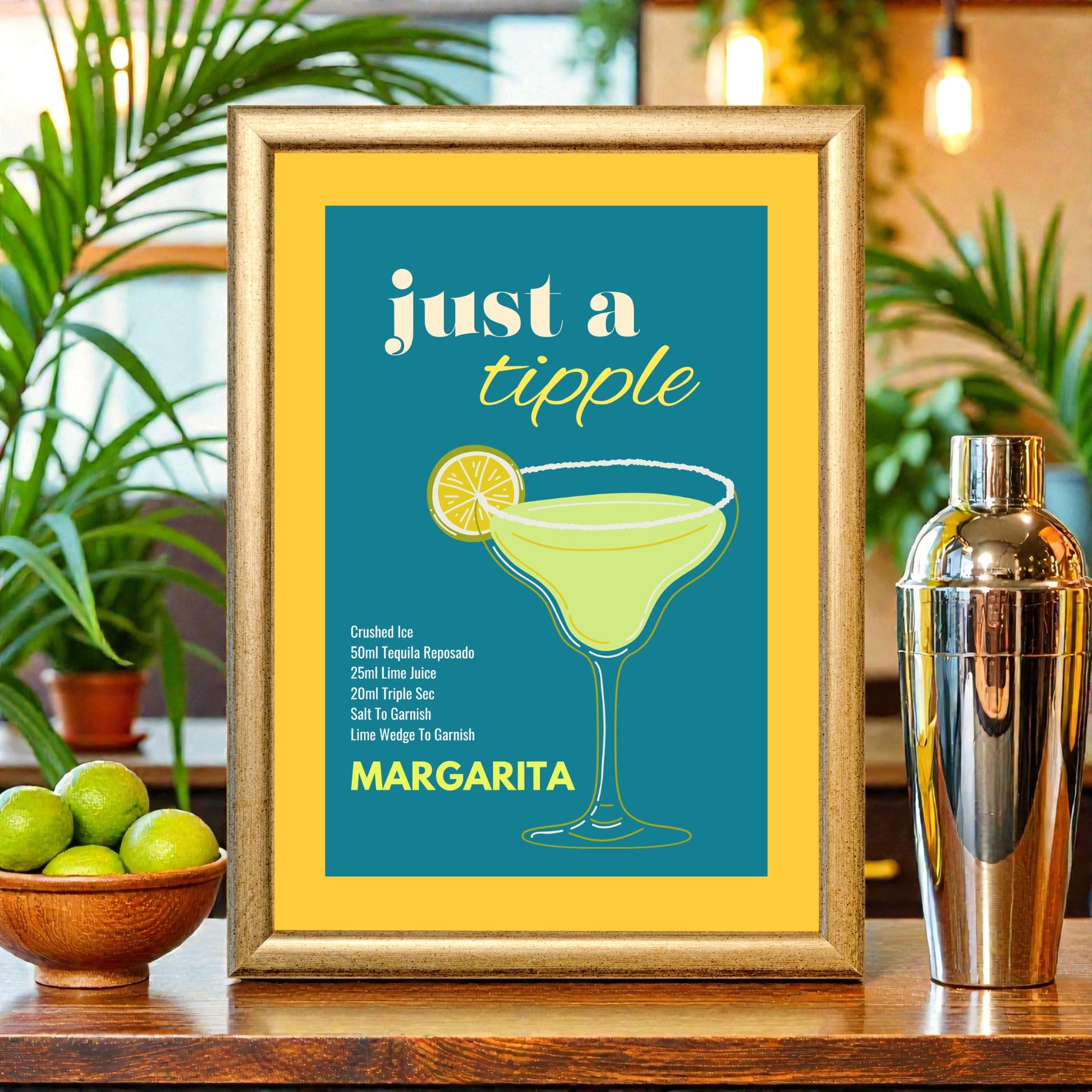 Framed margarita cocktail recipe print with teal and yellow design, illustrated margarita glass and lime, displayed on a bar counter with limes, plants, and a cocktail shaker.