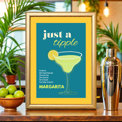 Framed margarita cocktail recipe print with teal and yellow design, illustrated margarita glass and lime, displayed on a bar counter with limes, plants, and a cocktail shaker.