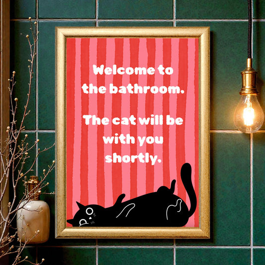 Framed poster with a red background and black cat illustration, text 'Welcome to the bathroom. The cat will be with you shortly.