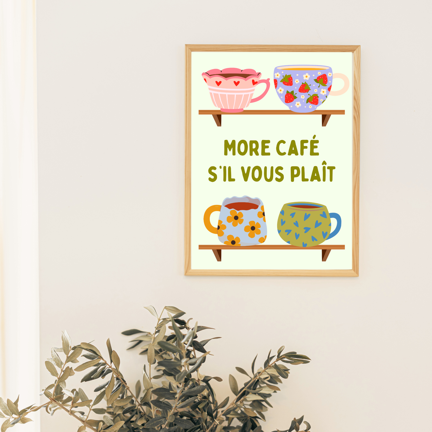 Framed artwork with colorful mugs and text 'More Café S'il Vous Plait' on a white wall.